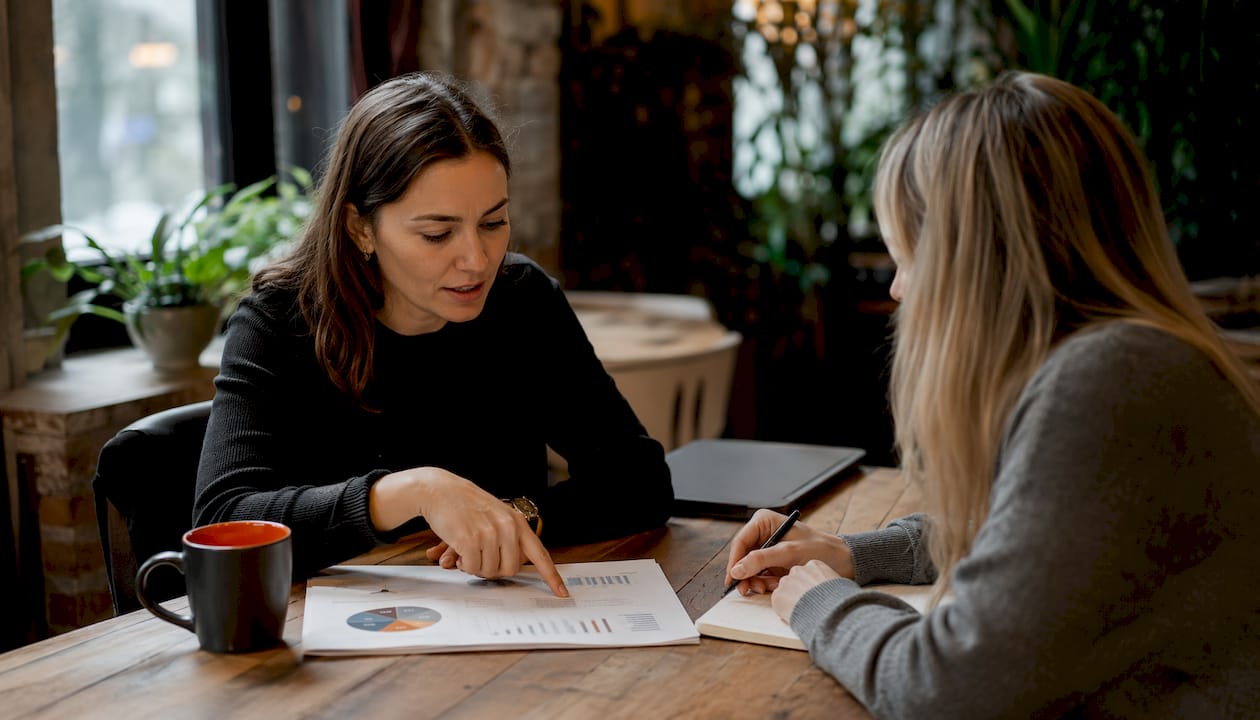 Zwei Kollegen sitzen in einem Café und tauschen sich angeregt über Möglichkeiten zur Optimierung der Conversion-Rate aus.