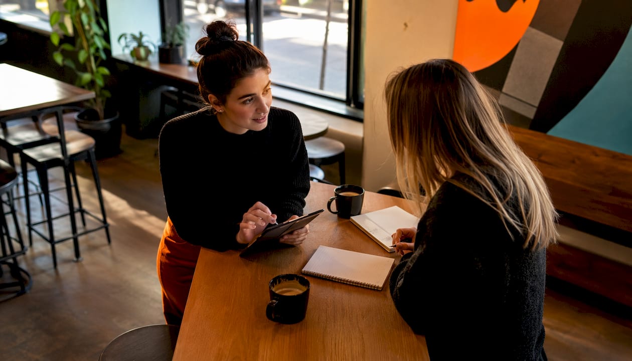 Eine Marketing-Expertin tauscht sich im Coworking-Space über Strategien für Meta Ads aus.
