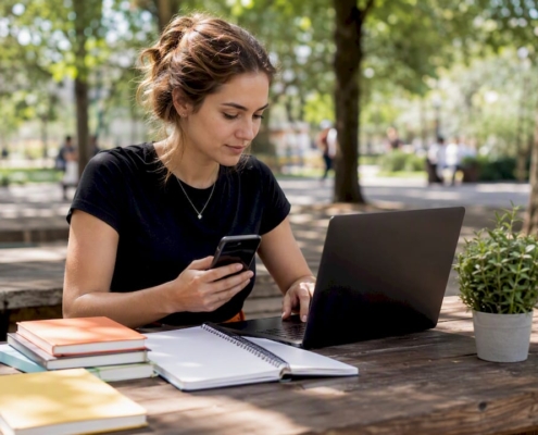 Eine Frau steuert ihre Google Ads-Kampagnen sowohl am Smartphone als auch am Laptop.