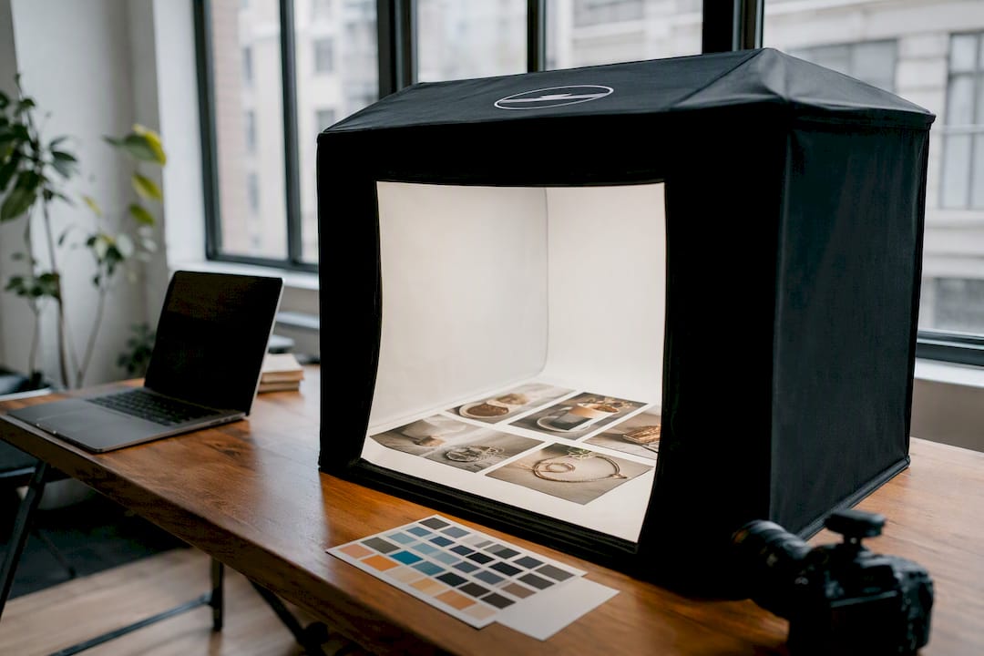Produktfotos und eine Lichtbox auf einem Holztisch arrangiert