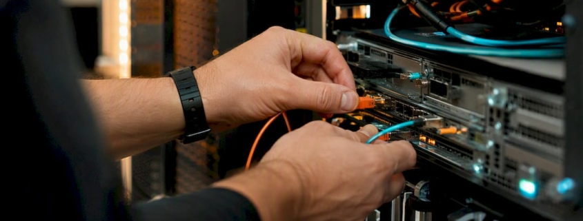 Ein Techniker schließt im Serverschrank ein Netzwerkkabel an.