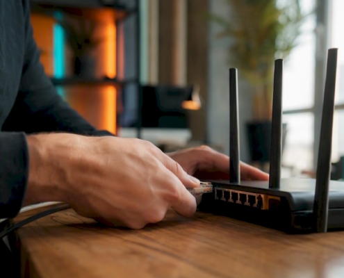 Hände, die ein Ethernet-Kabel mit dem Router verbinden