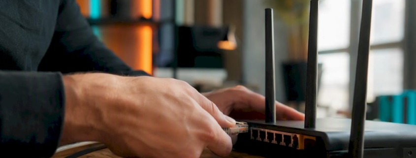 Hände, die ein Ethernet-Kabel mit dem Router verbinden