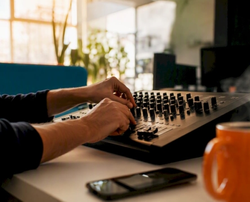Hände, die die Regler eines Audio-Mischpults justieren