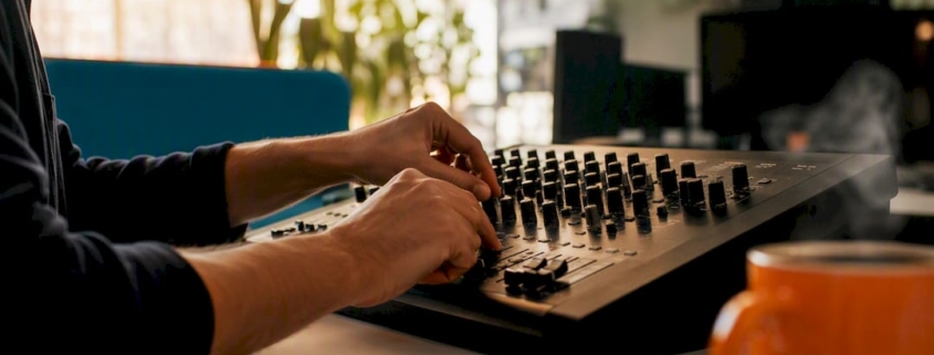Hände, die die Regler eines Audio-Mischpults justieren